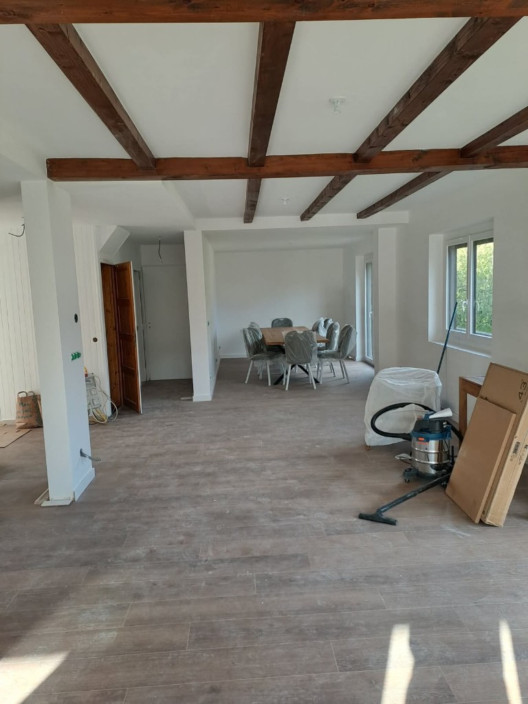 Pièce à vivre ouverte en phase de finition, poutres apparentes et sol bois