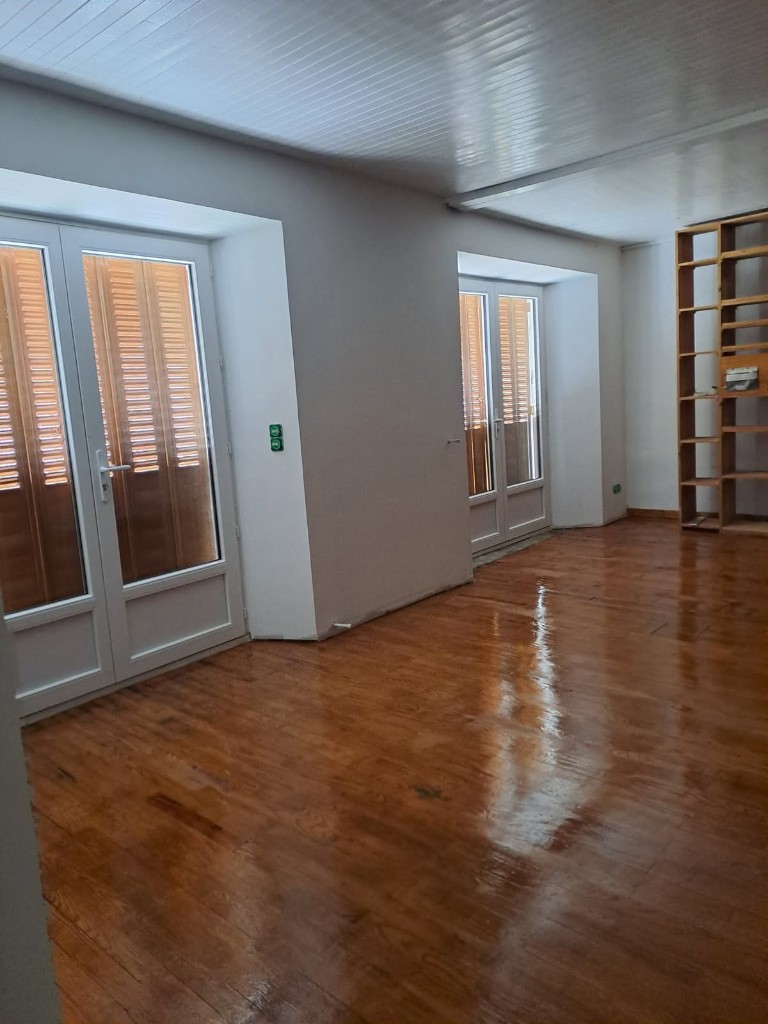 Pièce finie avec sol bois brillant, portes-fenêtres et étagères sur mesure